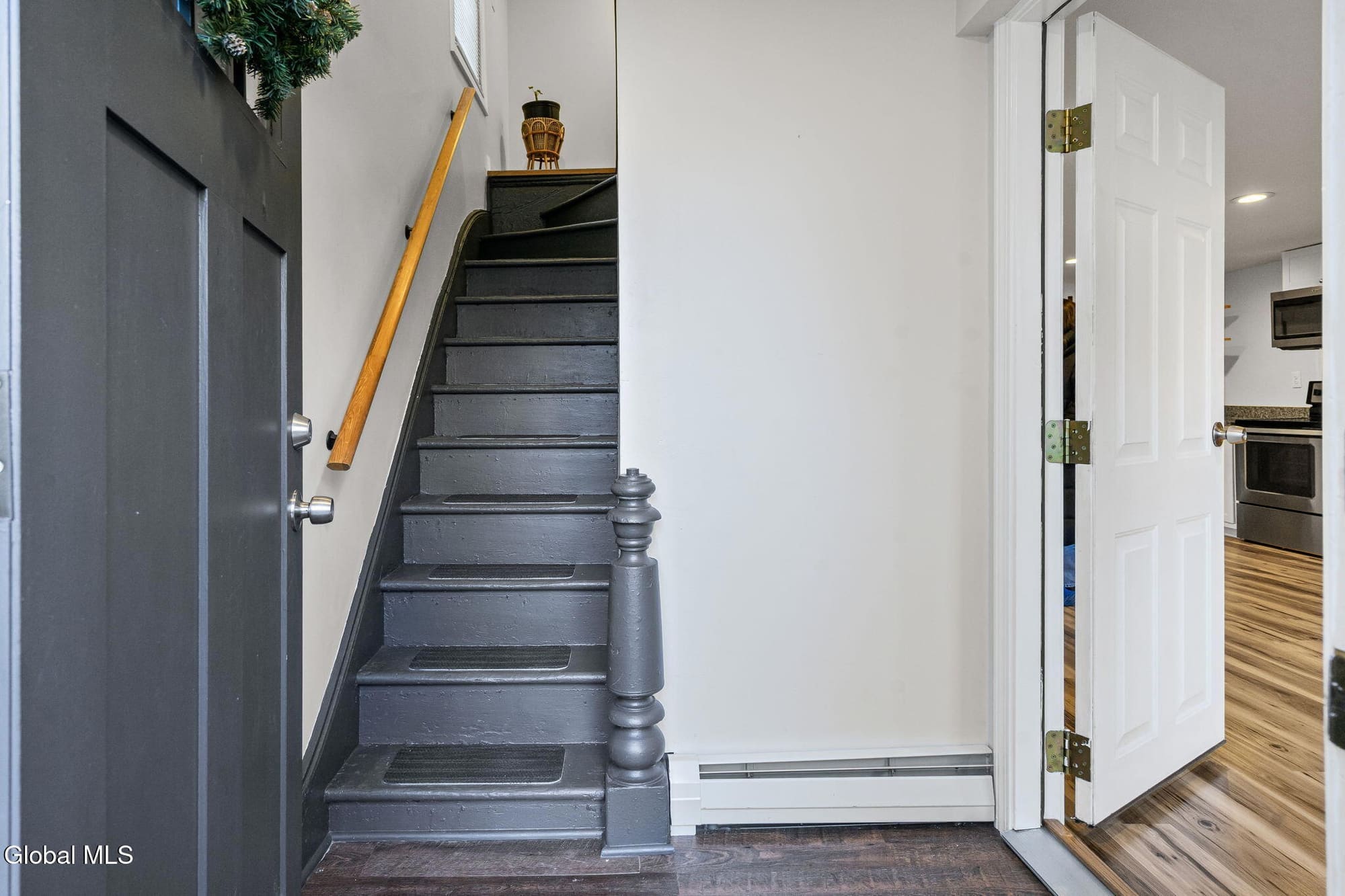 Dark wooden staircase with wooden handrail in modern home entryway with white walls