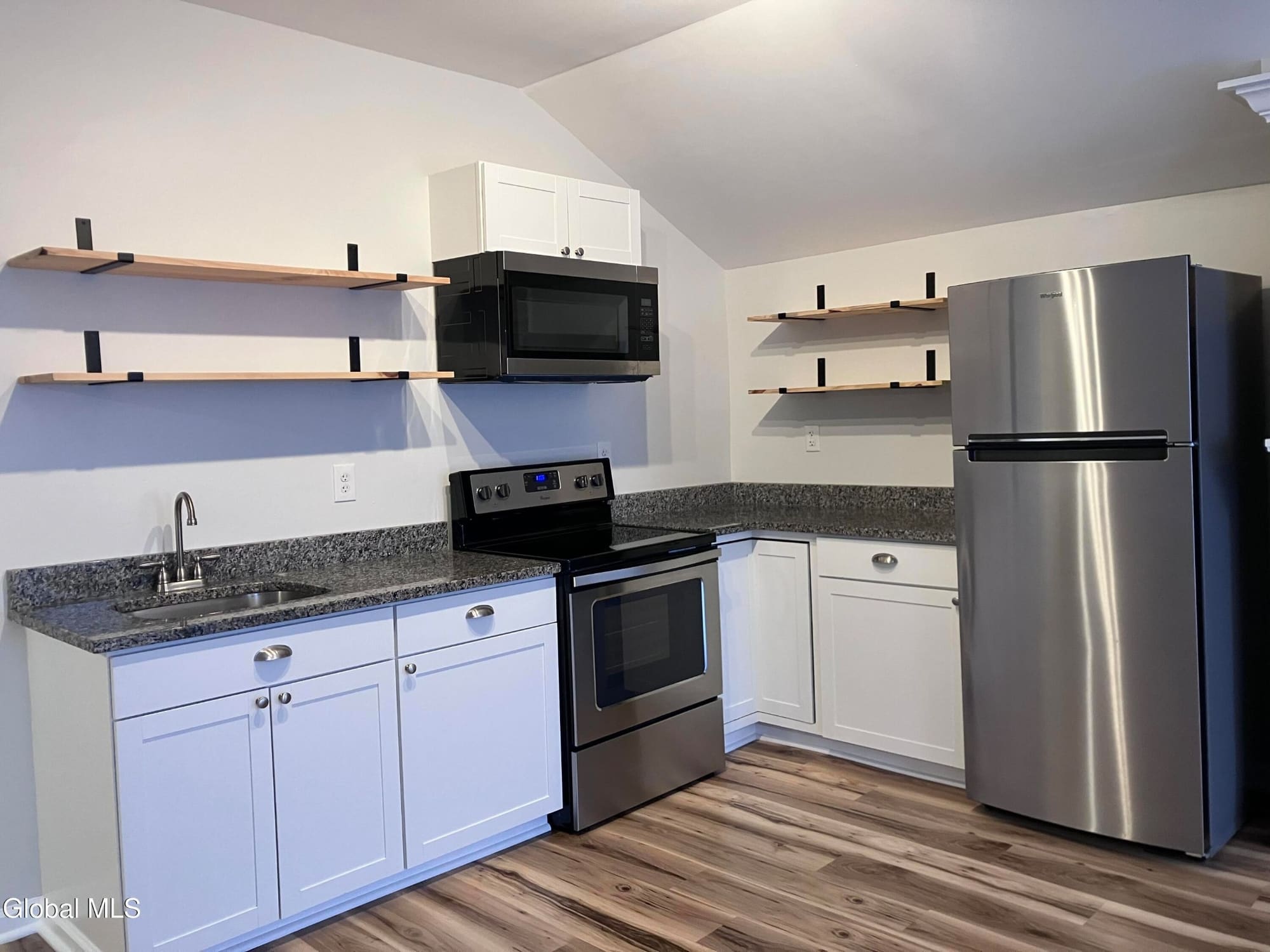 Modern kitchen with white cabinets, stainless steel appliances, granite countertops and wooden shelving