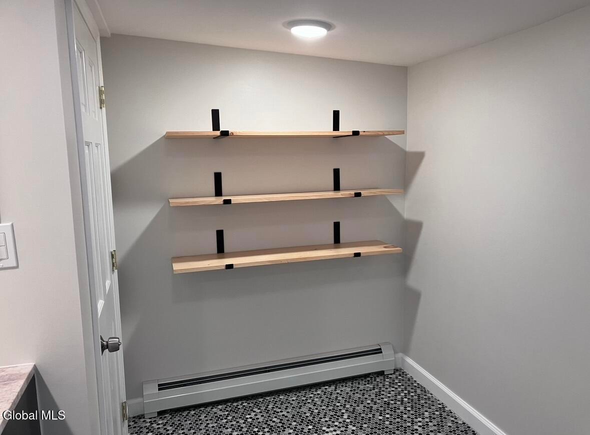 Three wooden shelves with black brackets mounted on gray wall in finished room