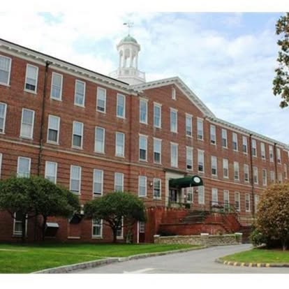 Red brick academic building with white trim, cupola, and manicured grounds