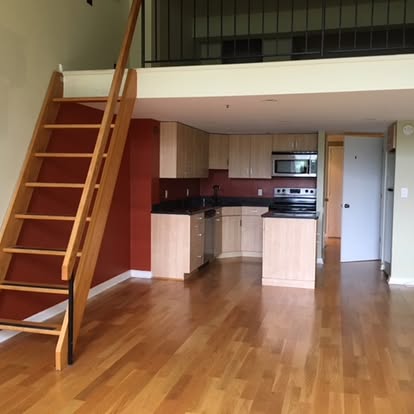 Modern loft apartment with wooden staircase, open kitchen, and hardwood floors