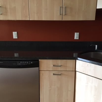Modern kitchen countertop with stainless steel appliances and light wood cabinetry