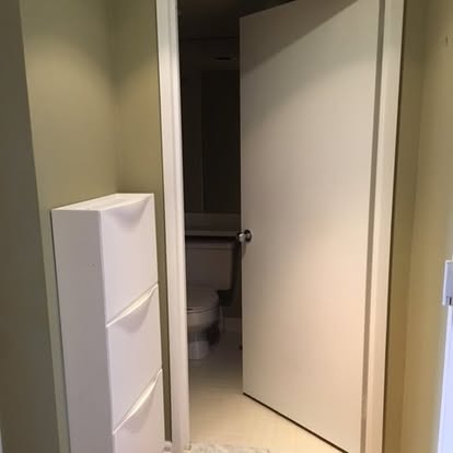 Open doorway leading to a bathroom with toilet and white storage cabinet visible