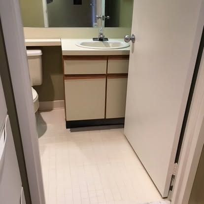 Modern bathroom vanity with round sink, mirror, and tile flooring viewed from doorway