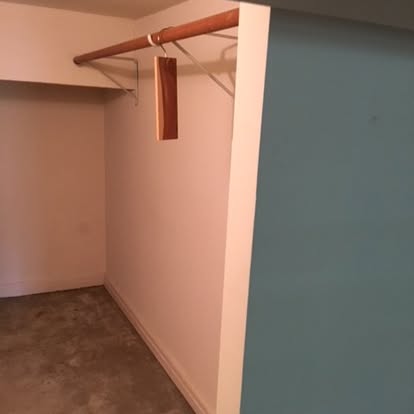 Empty closet with wooden rod and pink walls