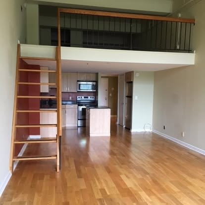 Modern loft apartment with mezzanine level, wooden stairs, and open kitchen