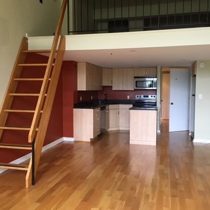 Modern loft apartment with wooden staircase, open kitchen, and hardwood floors