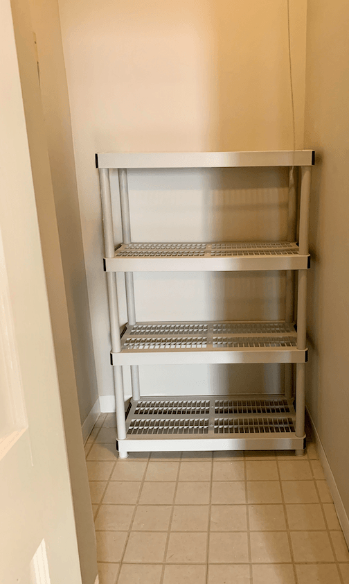 White metal shelving unit with three wire shelves in empty pantry closet