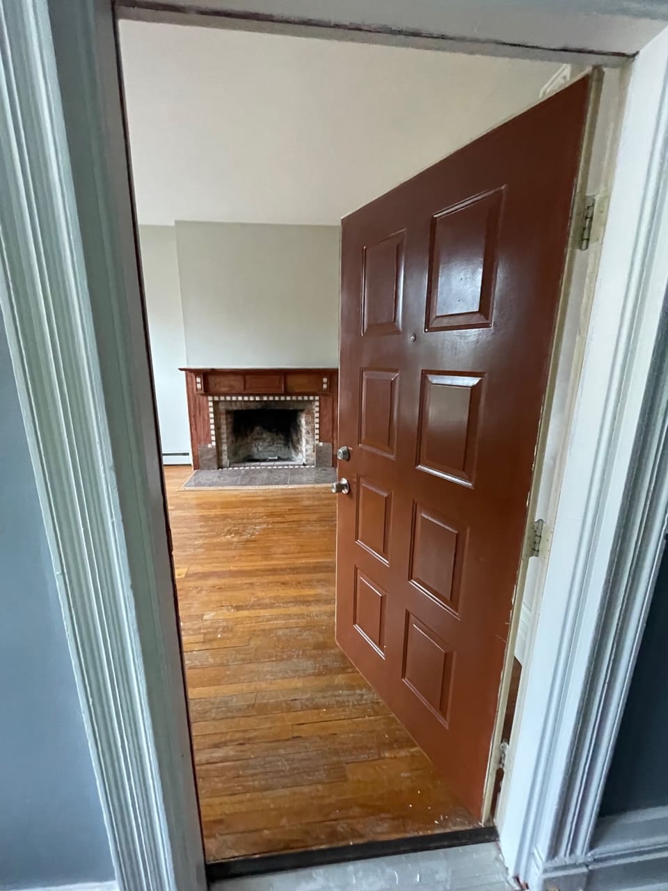 Interior doorway opening into living room with fireplace and wooden flooring