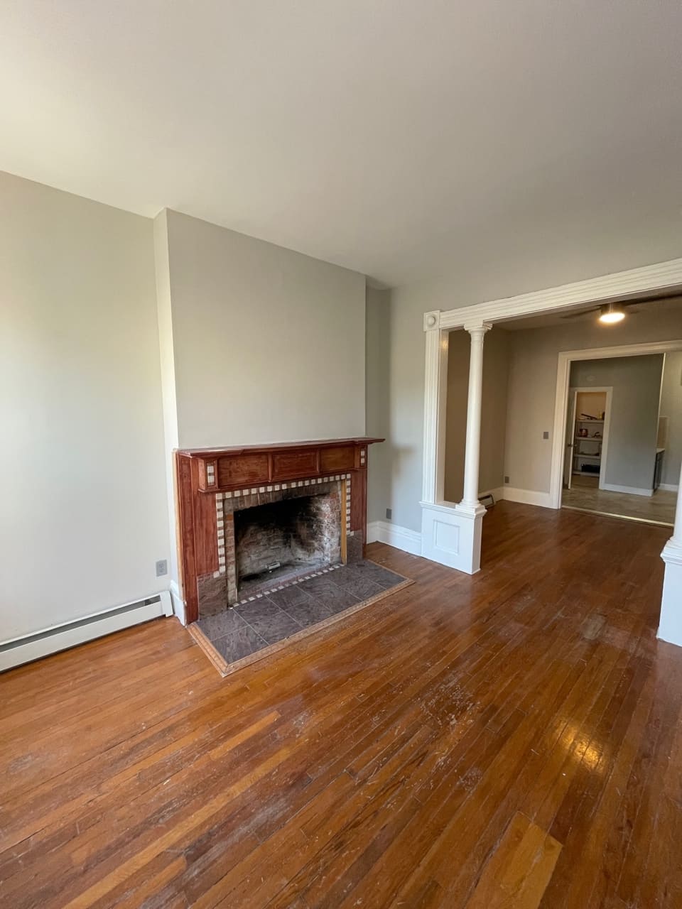 Spacious living room with fireplace, hardwood floors, and white trim doorway
