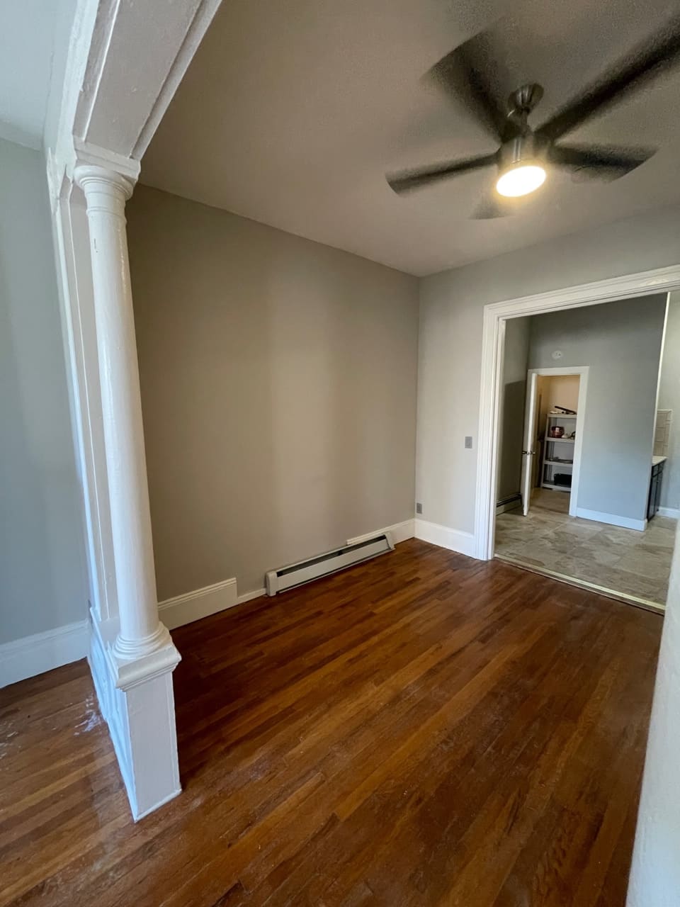 Empty bedroom with hardwood floors, ceiling fan, and mirrored closet door