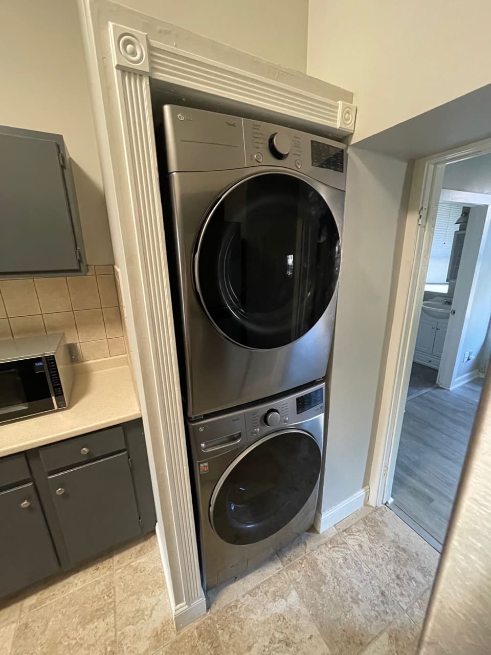 Stacked washer and dryer unit in laundry room alcove with decorative molding